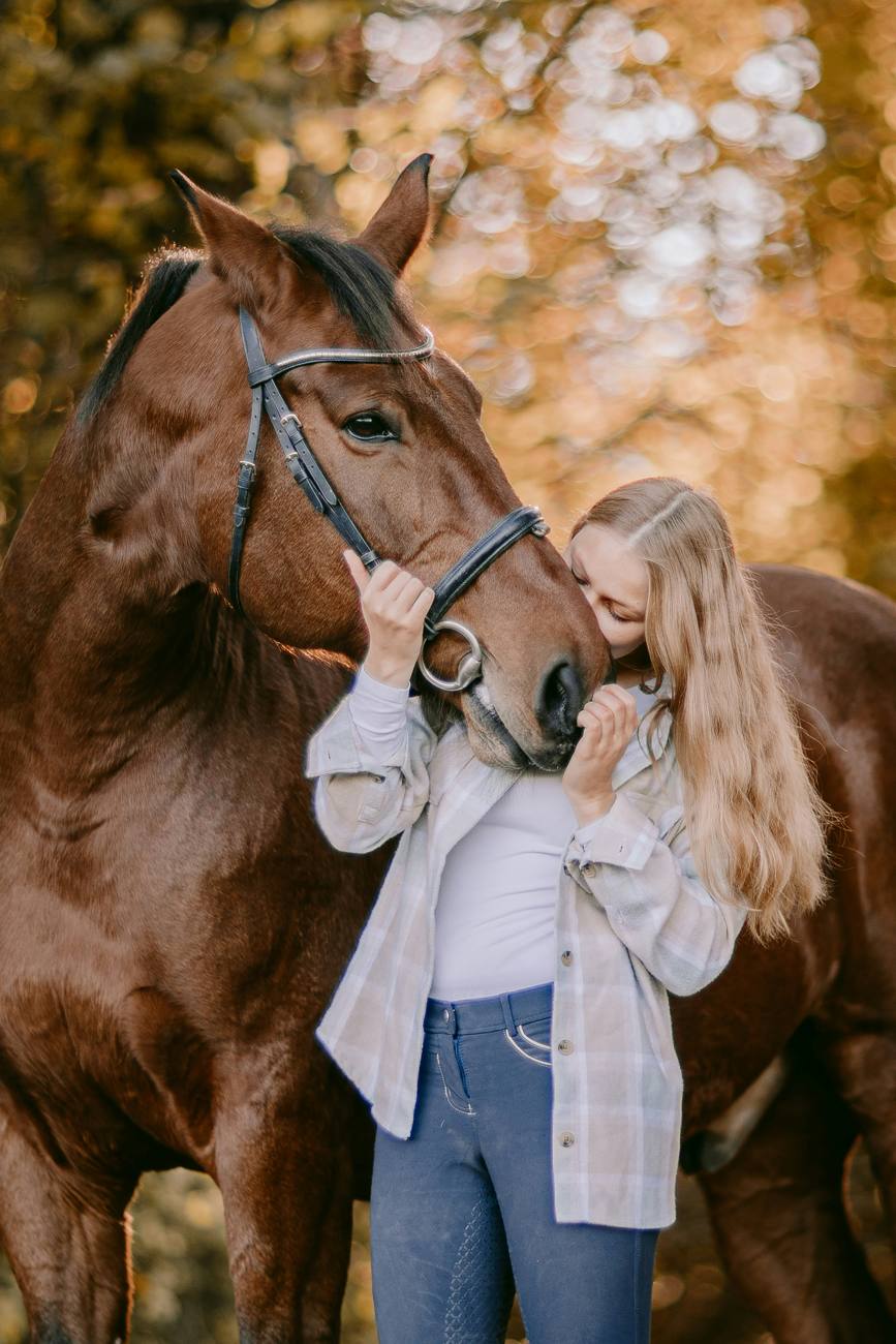 Une jeune femme embrasse le museau de son cheval